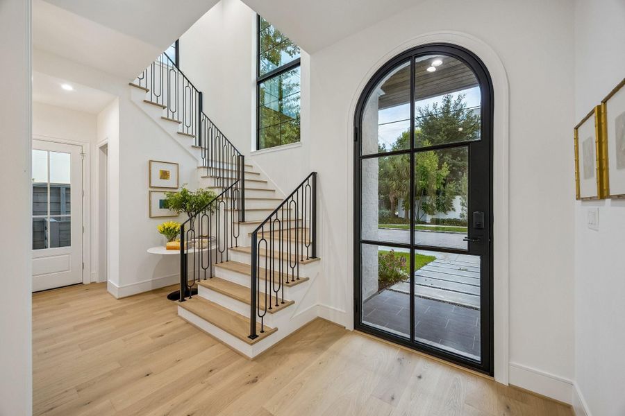 Large Foyer with a Dramatic Staircase and a 30” Wellmet Coastal Capiz Shell Chandelier.  Oak Treads on all Stairs and Solid Wrought Iron Railing with Modern Oval Balusters.