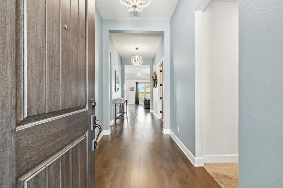 Foyer entrance featuring dark wood-type flooring and a chandelier Foyer entrance featuring dark wood-type flooring and a chandelier