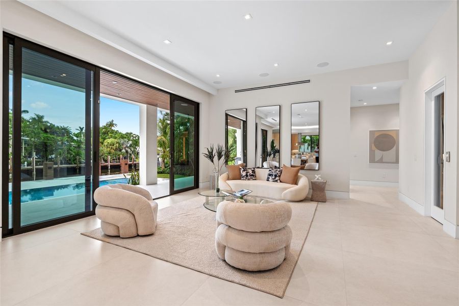 Stylish living room with modern designer furnishings, glass walls opening to the pool, and seamless indoor-outdoor living. Stylish living room with modern designer furnishings, glass walls opening to the pool, and seamless indoor-outdoor living.