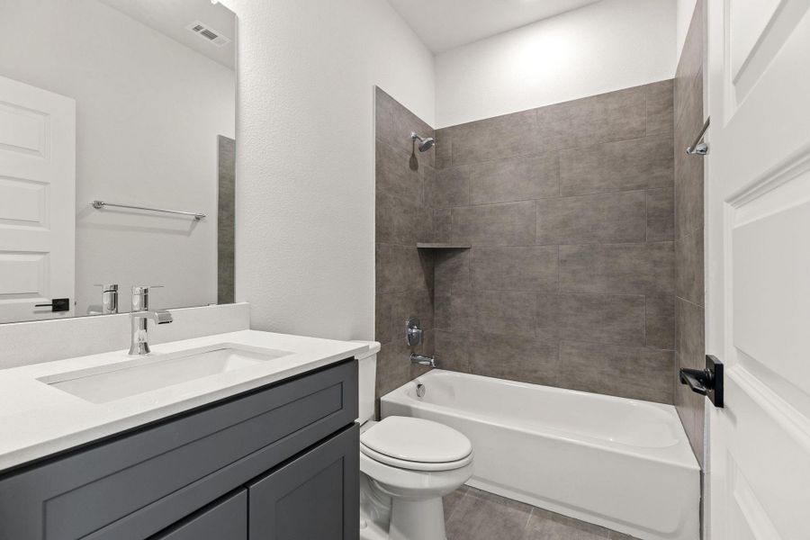 A well-appointed bathroom featuring a contemporary vanity and sleek tiled shower surround.