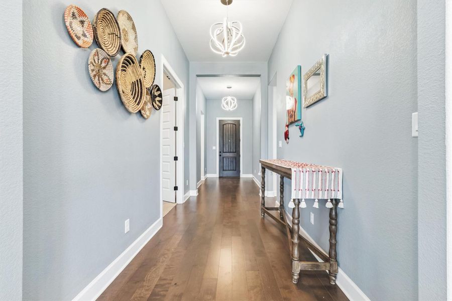 Hallway featuring dark wood-style flooring and a chandelier Hallway featuring dark wood-style flooring and a chandelier
