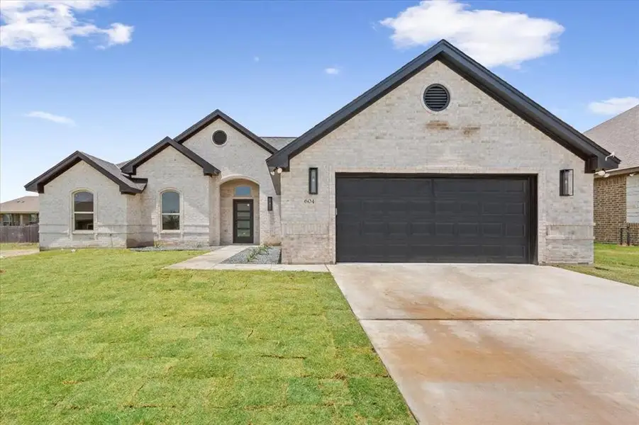 French country style house with brick siding, a front lawn, driveway, and a garage French country style house with brick siding, a front lawn, driveway, and a garage