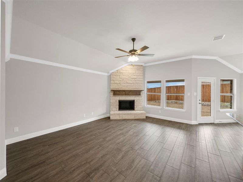 Unfurnished living room with a fireplace, a ceiling fan, vaulted ceiling, visible vents, and dark wood-style floors Unfurnished living room with a fireplace, a ceiling fan, vaulted ceiling, visible vents, and dark wood-style floors