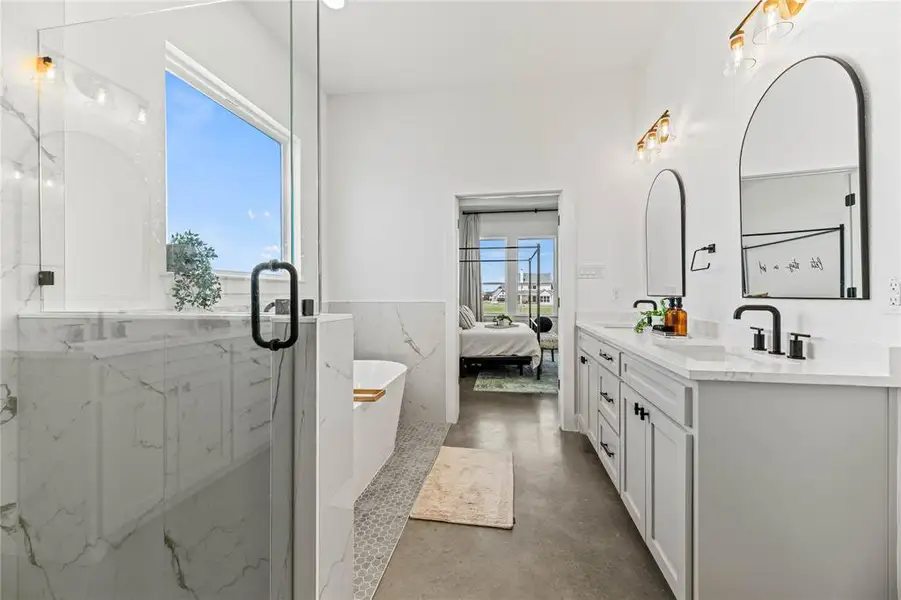 Bathroom featuring double vanity, concrete floors, a freestanding tub, connected bathroom, and wainscoting Bathroom featuring double vanity, concrete floors, a freestanding tub, connected bathroom, and wainscoting