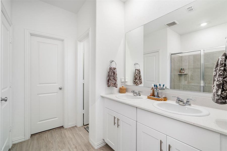 The bathroom features a double vanity with white cabinetry and a light-colored countertop