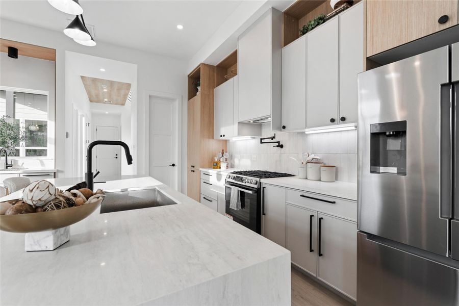 From the sculptural faucet to the tailored storage above, this kitchen balances modern precision with organic warmth. The result is a setting that feels composed, inviting, and distinctly architectural.