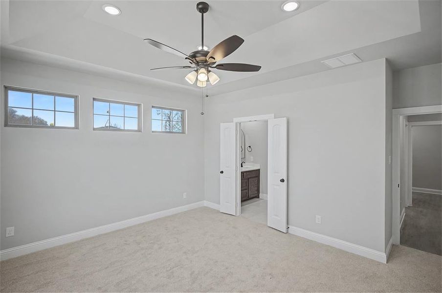 Unfurnished bedroom featuring light colored carpet, recessed lighting, a ceiling fan, and ensuite bathroom