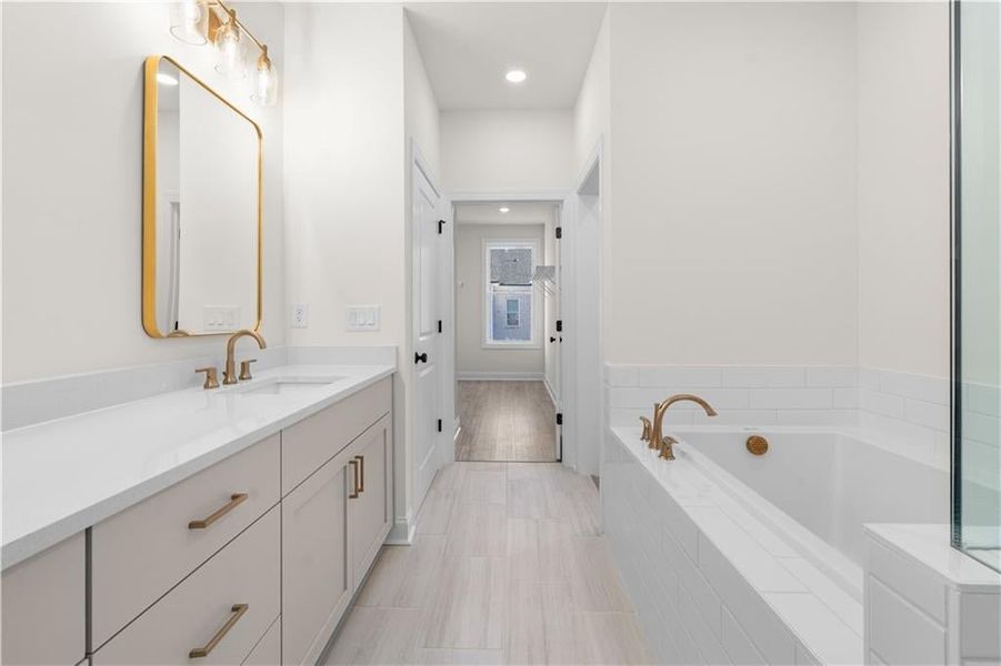 Bathroom featuring vanity, a bath, and recessed lighting