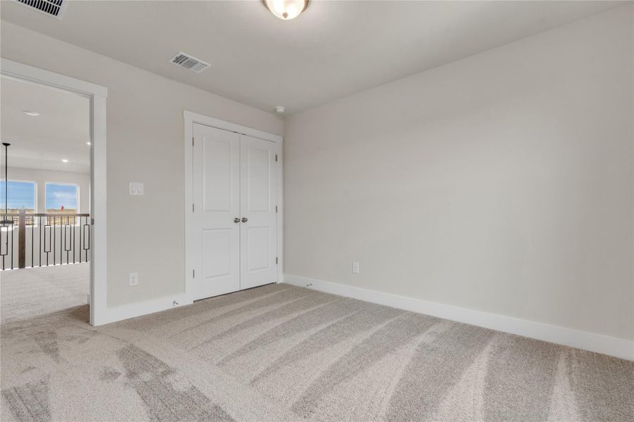 A quiet, carpeted room with a double-door closet and a view into an open-concept area.