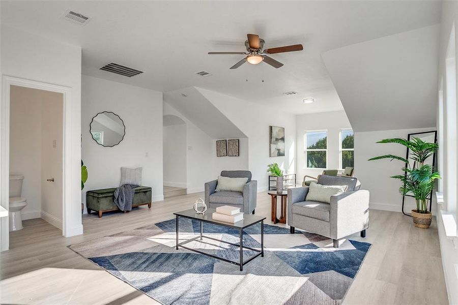 Living room featuring light wood-style flooring and a ceiling fan Living room featuring light wood-style flooring and a ceiling fan