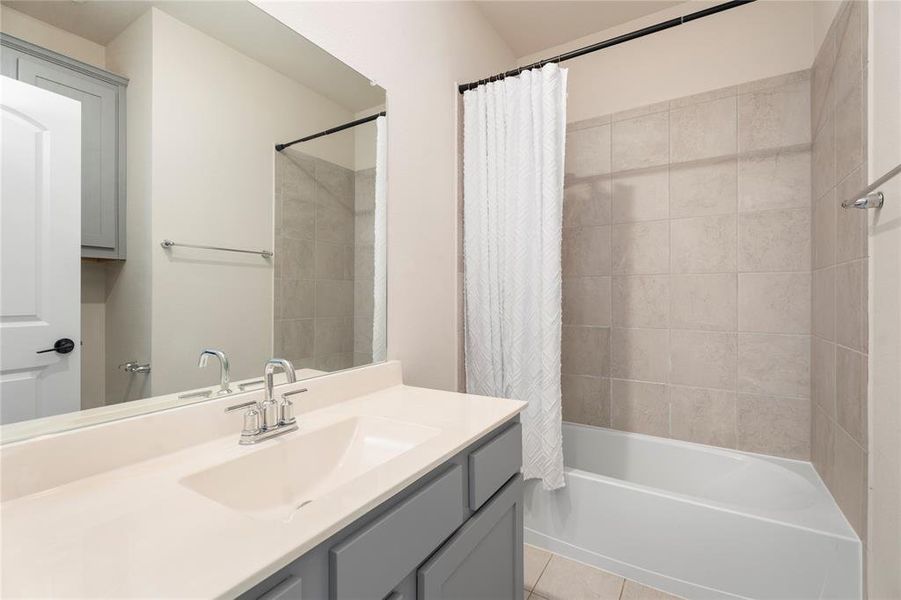 Full bath featuring vanity, shower / tub combo, and tile patterned floors