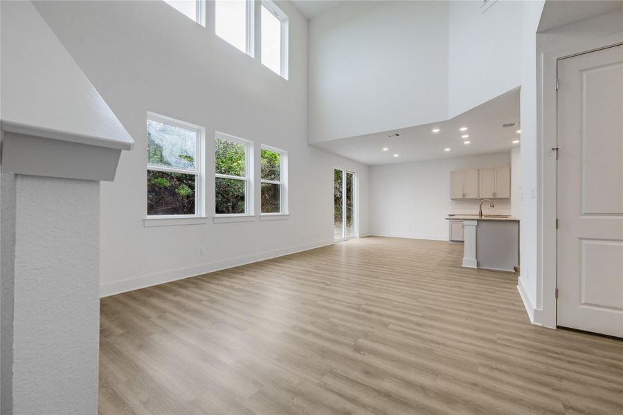 Tons of natural light, light wood-style flooring, a high ceiling, and recessed lighting.