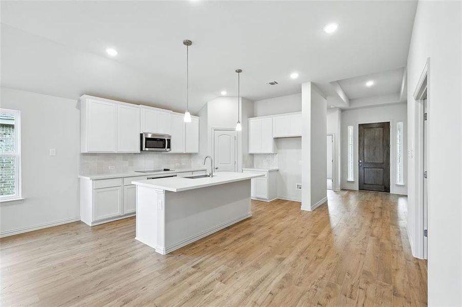 Kitchen featuring white cabinetry, light wood-style floors, hanging light fixtures, tasteful backsplash, and recessed lighting Kitchen featuring white cabinetry, light wood-style floors, hanging light fixtures, tasteful backsplash, and recessed lighting