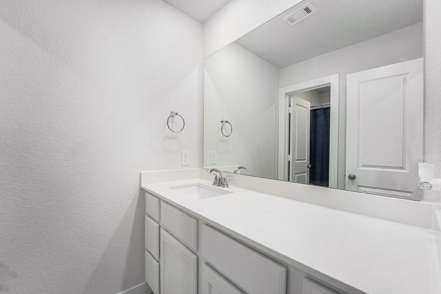 Upstairs bath with quartz countertop, modern fixtures, and ample storage.