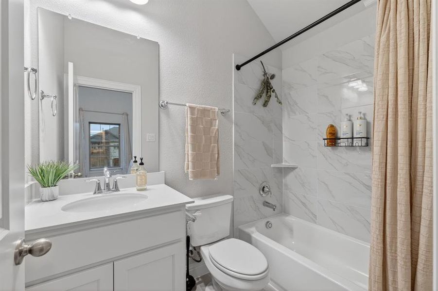 Full bathroom featuring shower / tub combo, vanity, and a textured wall Full bathroom featuring shower / tub combo, vanity, and a textured wall