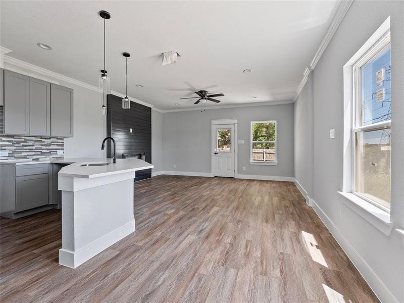 Kitchen featuring a sink, gray cabinets, light countertops, ornamental molding, and backsplash