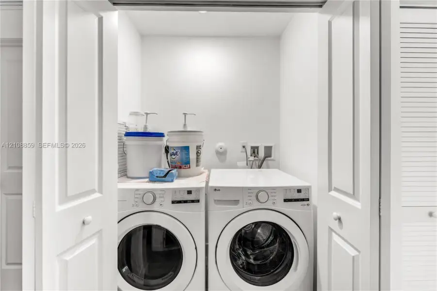 Laundry closet featuring louvered bi-fold doors, white interior finishes, and dedicated utility hookups