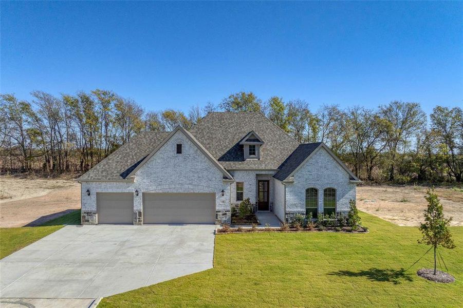 French country home with brick siding, concrete driveway, a front lawn, and an attached garage French country home with brick siding, concrete driveway, a front lawn, and an attached garage