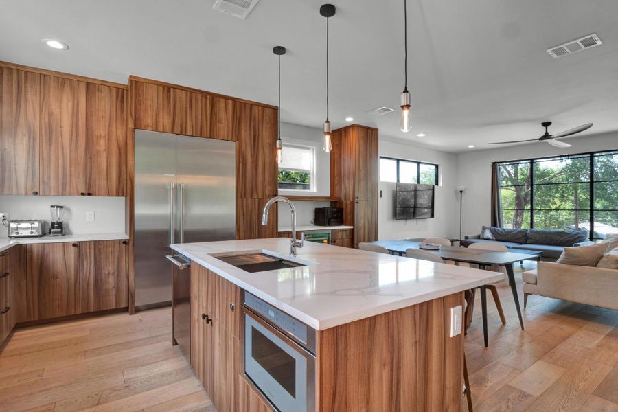 Kitchen featuring brown cabinets, built in appliances, open floor plan, light wood finished floors, and recessed lighting