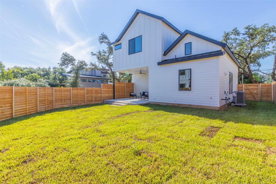 Back of house with a patio area, board and batten siding, a fenced backyard, and ceiling fan