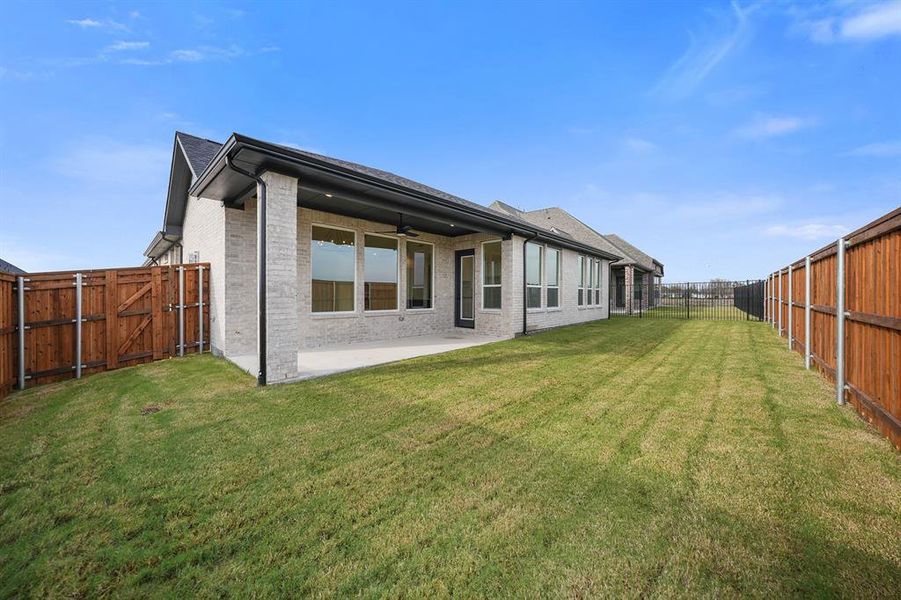 Back of property with a gate, a ceiling fan, a fenced backyard, brick siding, and a patio area