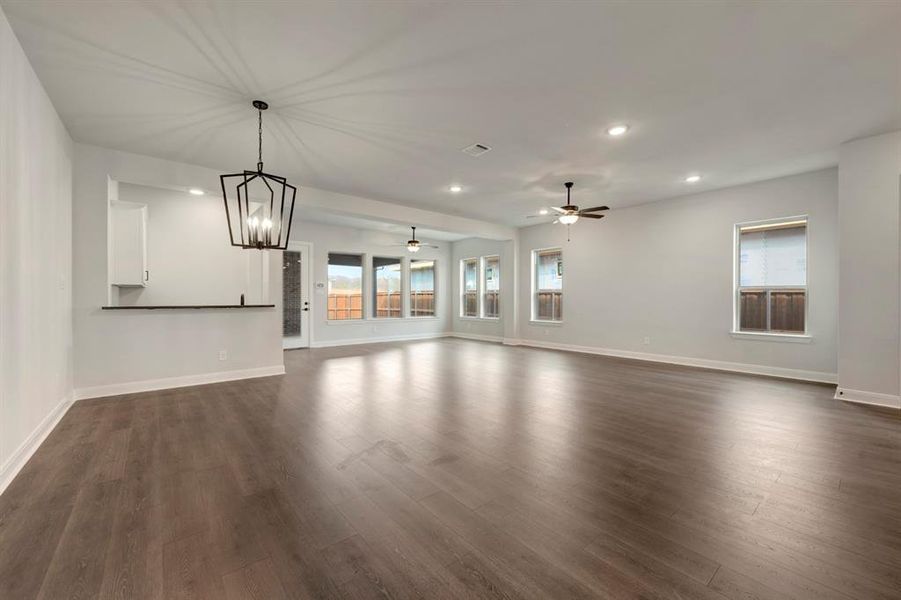Unfurnished living room featuring suspended lighting, dark wood finished floors, and a ceiling fan