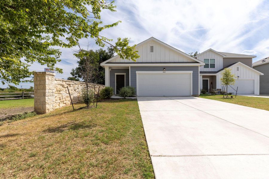 View of front of property with board and batten siding, concrete driveway, and an attached garage View of front of property with board and batten siding, concrete driveway, and an attached garage