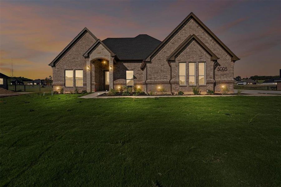 French provincial home featuring brick siding and a lawn