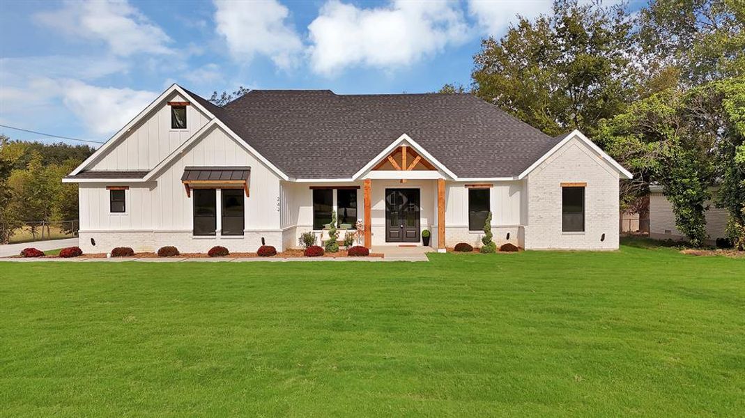 Modern inspired farmhouse with board and batten siding, a front lawn, a shingled roof, and covered porch Modern inspired farmhouse with board and batten siding, a front lawn, a shingled roof, and covered porch