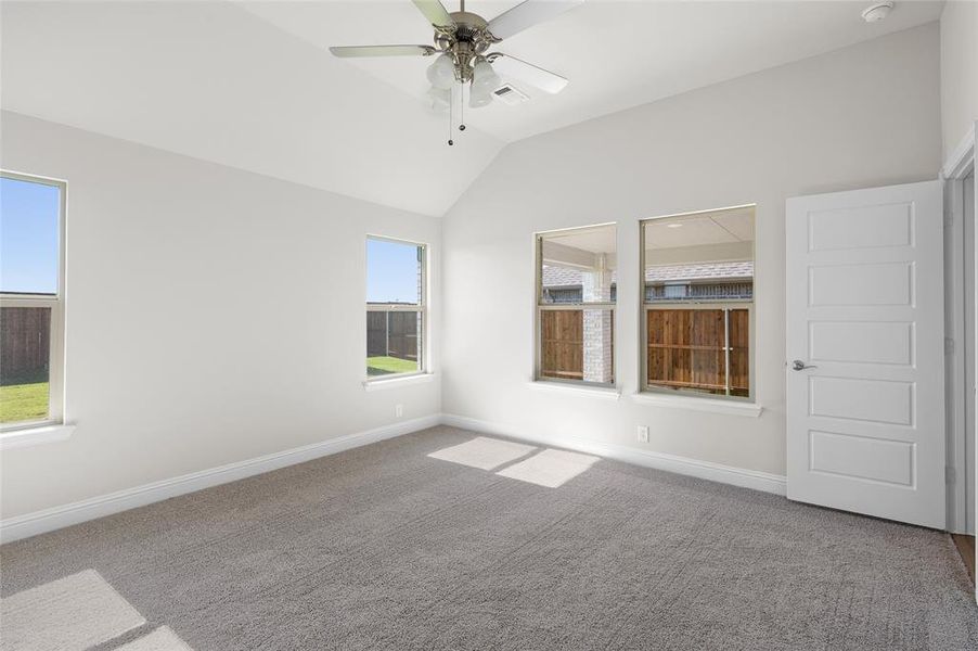 Spare room with vaulted ceiling, carpet, and a ceiling fan
