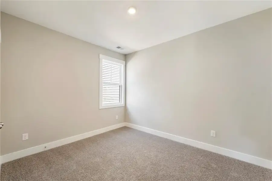 A well-lit bedroom with comfortable carpet and a w
