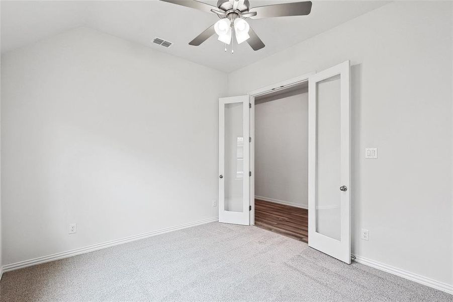 Unfurnished bedroom featuring carpet flooring, french doors, ceiling fan, vaulted ceiling, and a closet