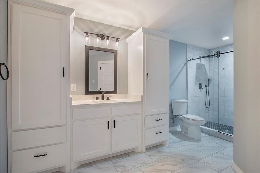 Bathroom with a shower with door, vanity, and toilet