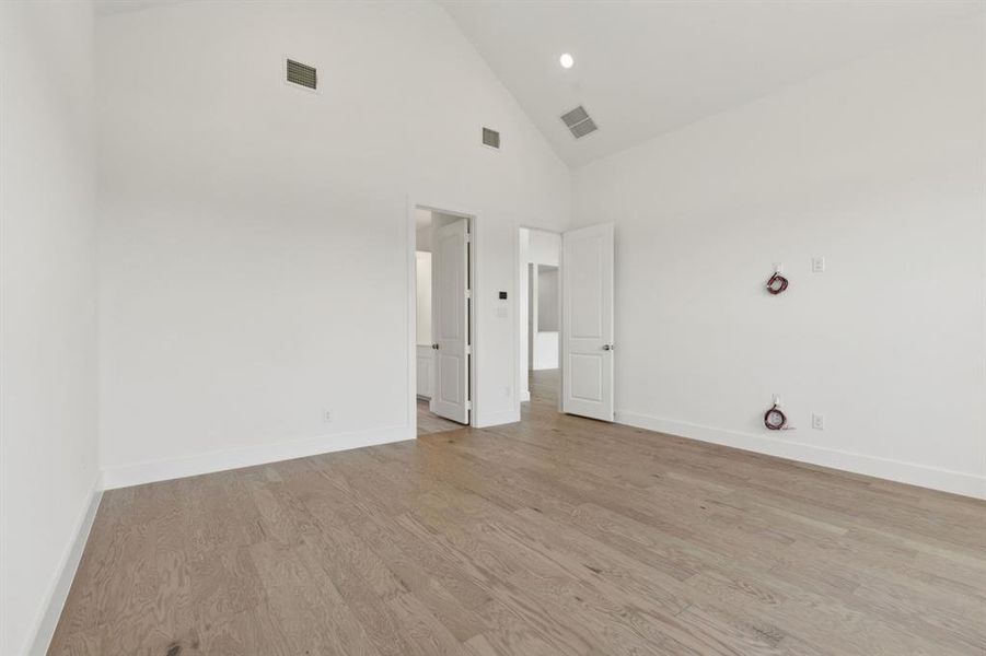 Expansive room featuring a vaulted ceiling and light wood-finish flooring Expansive room featuring a vaulted ceiling and light wood-finish flooring