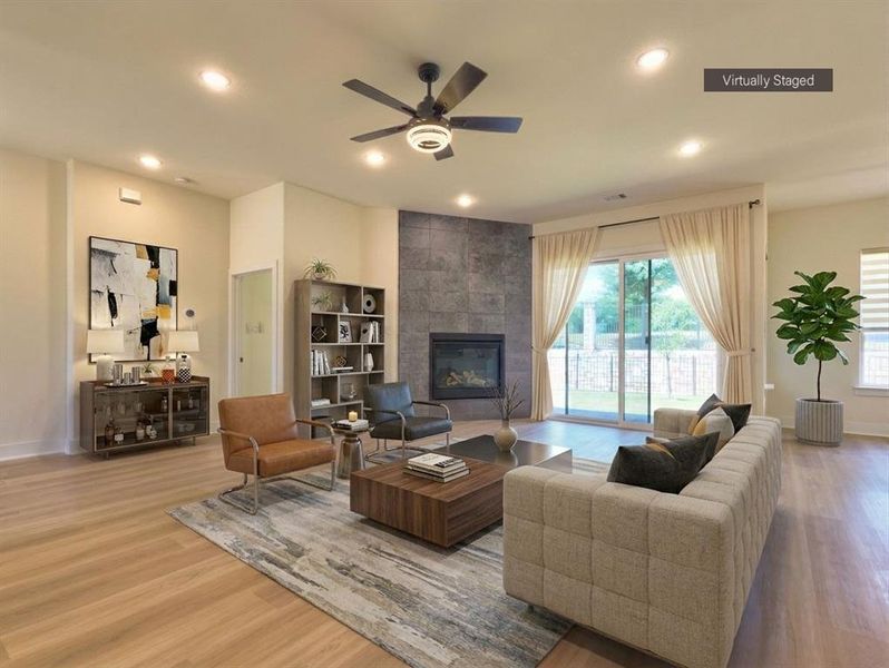 Spacious living area featuring wood-finish flooring, a stone-clad fireplace, recessed lighting, and a ceiling fan