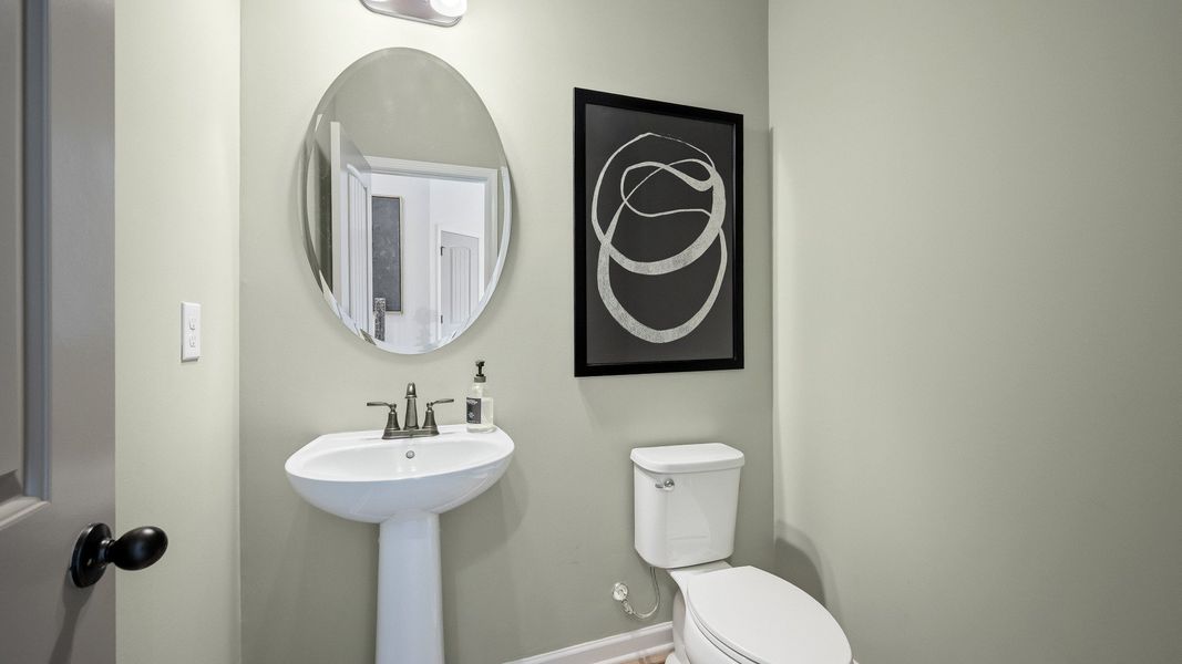 Elegant half bath with pedestal sink and modern fixtures in Langley Overlook townhome in Loganville, Georgia.