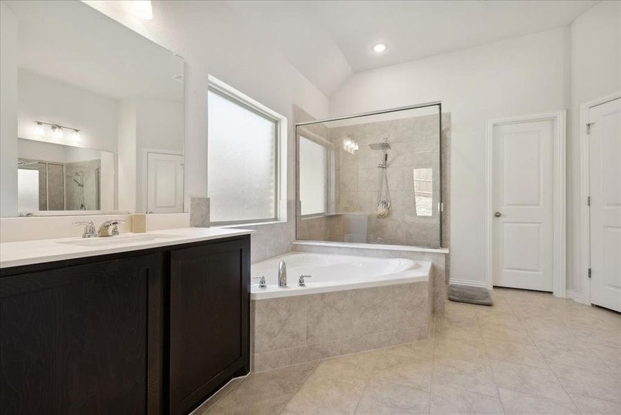 Bathroom with tile patterned flooring, vanity, lofted ceiling, and independent shower and bath