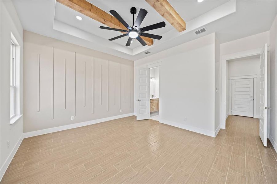 Unfurnished bedroom featuring a raised ceiling, recessed lighting, ensuite bathroom, ceiling fan, and wood finish floors Unfurnished bedroom featuring a raised ceiling, recessed lighting, ensuite bathroom, ceiling fan, and wood finish floors