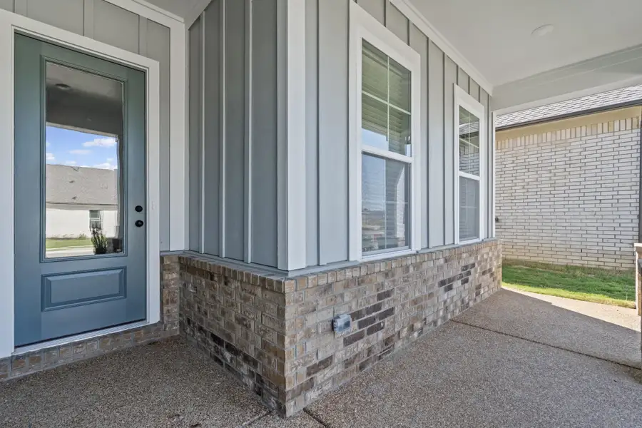 Entrance to property with brick siding, board and batten siding, and a porch
