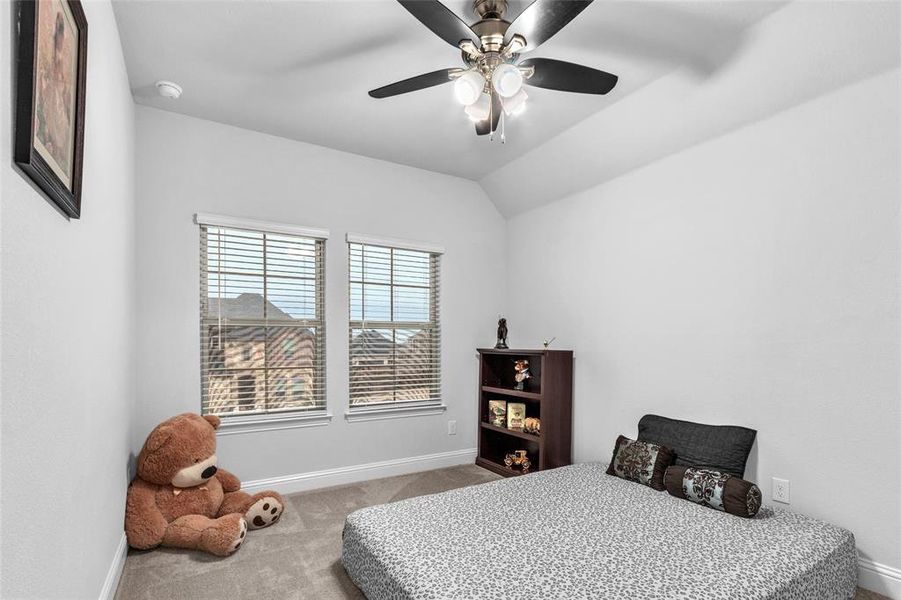 Bedroom with light carpet, ceiling fan, vaulted ceiling, and baseboards