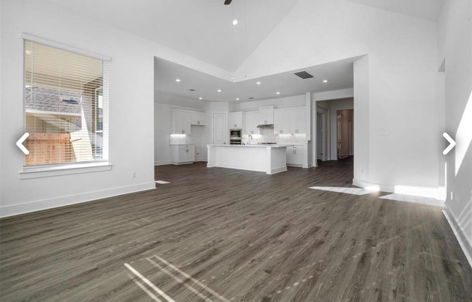 Unfurnished living room featuring dark wood-style flooring, vaulted ceiling, ceiling fan, and recessed lighting