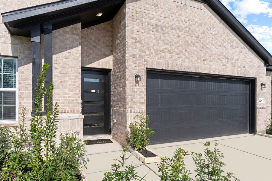 Step up to a warm and welcoming front entry that instantly feels like home. The covered porch, soft brick tones, and modern black trim create an inviting first impression that’s both stylish and timeless.  The custom stylish door opens to your memories today, come and visit us!