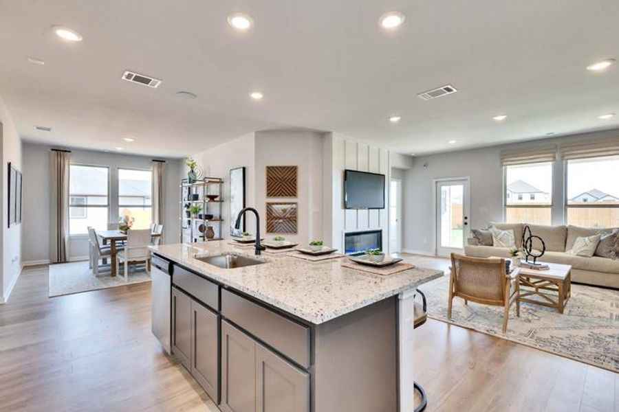 Kitchen featuring open floor plan, a kitchen island with sink, visible vents, and light stone countertops