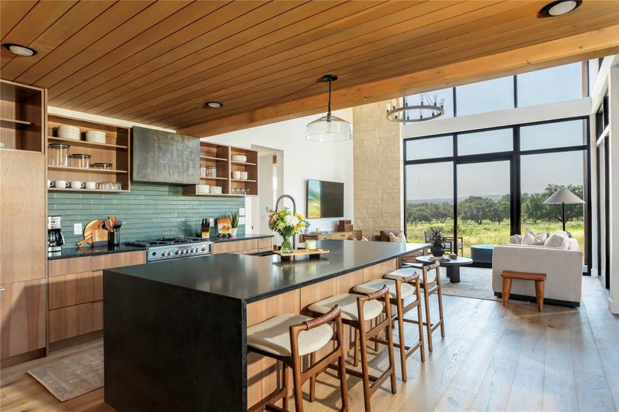 Open-concept kitchen and living space featuring soaring ceilings, oversized windows, and panoramic Hill Country views filled with natural light.
