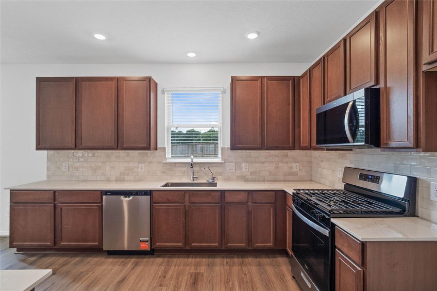 This stunning kitchen boasts high ceilings, recessed lighting, Woodmont Cody cabinets in Ginger stain, Silestone Bonze Rivers countertops, stainless steel Whirlpool appliances, a modern Daltile backsplash, an added breakfast bar, and a pantry—all overlooking the expansive Great Room. This stunning kitchen boasts high ceilings, recessed lighting, Woodmont Cody cabinets in Ginger stain, Silestone Bonze Rivers countertops, stainless steel Whirlpool appliances, a modern Daltile backsplash, an added breakfast bar, and a pantry—all overlooking the expansive Great Room.