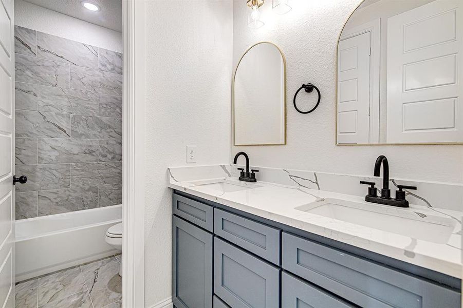 Bathroom with a textured wall, double vanity, and  shower combination
