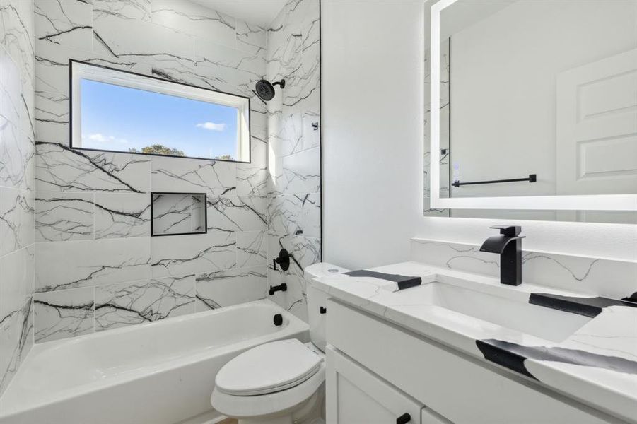 Full bathroom featuring vanity, toilet, and tiled shower / bath combo