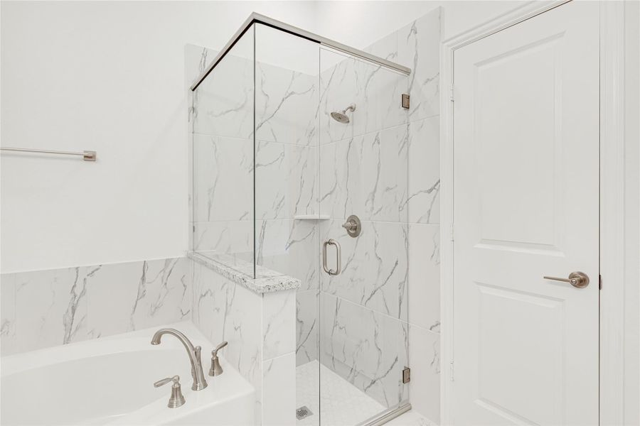 Bathroom with marble tile walls, glass-enclosed shower, and soaking tub with brushed nickel fixtures Bathroom with marble tile walls, glass-enclosed shower, and soaking tub with brushed nickel fixtures