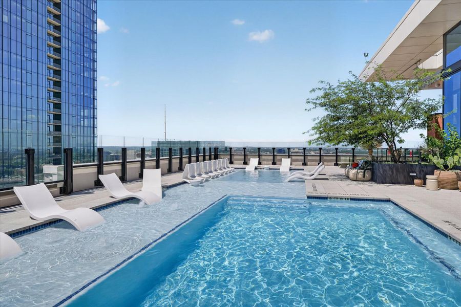 Rooftop oasis with shimmering pool and in-water loungers provides a captivating urban view.