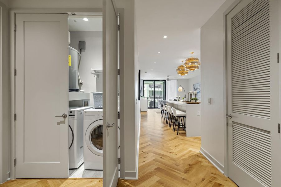 Herringbone hardwood floors extend through this open-concept living space, featuring a convenient laundry closet.
